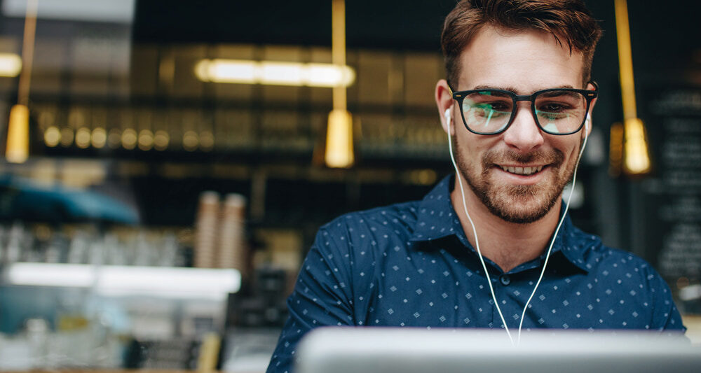 Person looking at a laptop screen, with earphones in