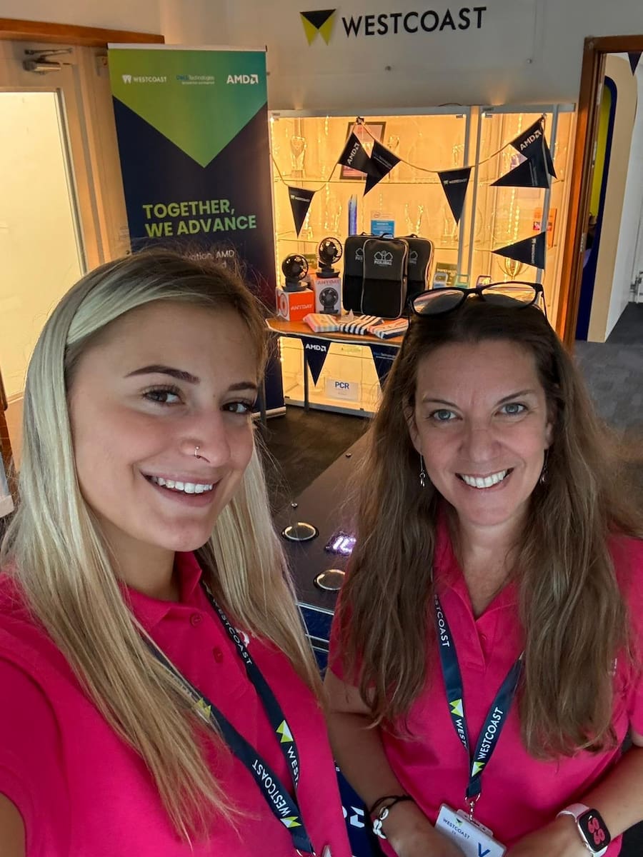 Two team members in pink tops smiling at an event